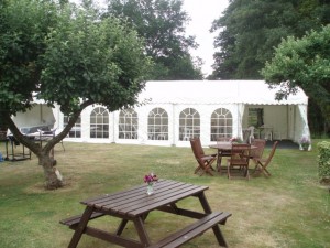 A 6m Marquee with Georgian window walls and white bistro chairs for a garden party in Crondall Hampshire